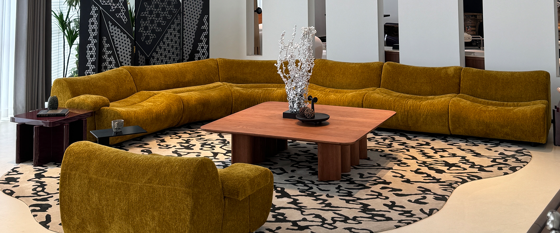 Curved sofa, patterned rug and timber tables in a SAMYAM living room